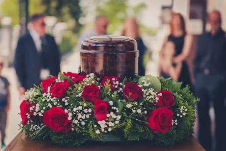 Urne cinéraire entourée d'une couronne de fleurs rouges