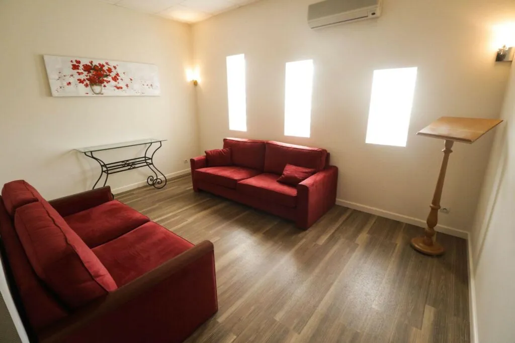 Espace d'accueil et salon de recueillement avec canapés rouges